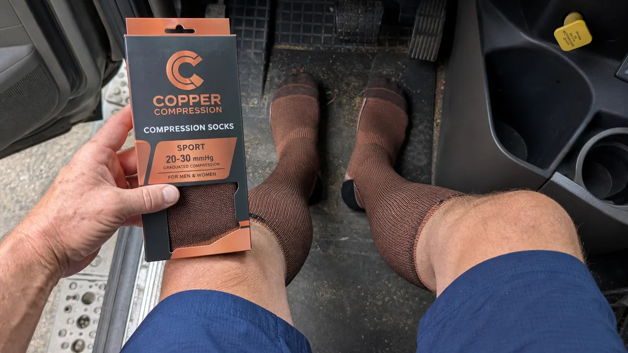 Driver's legs visible in cab seat, wearing compression socks, feet resting on floormat
